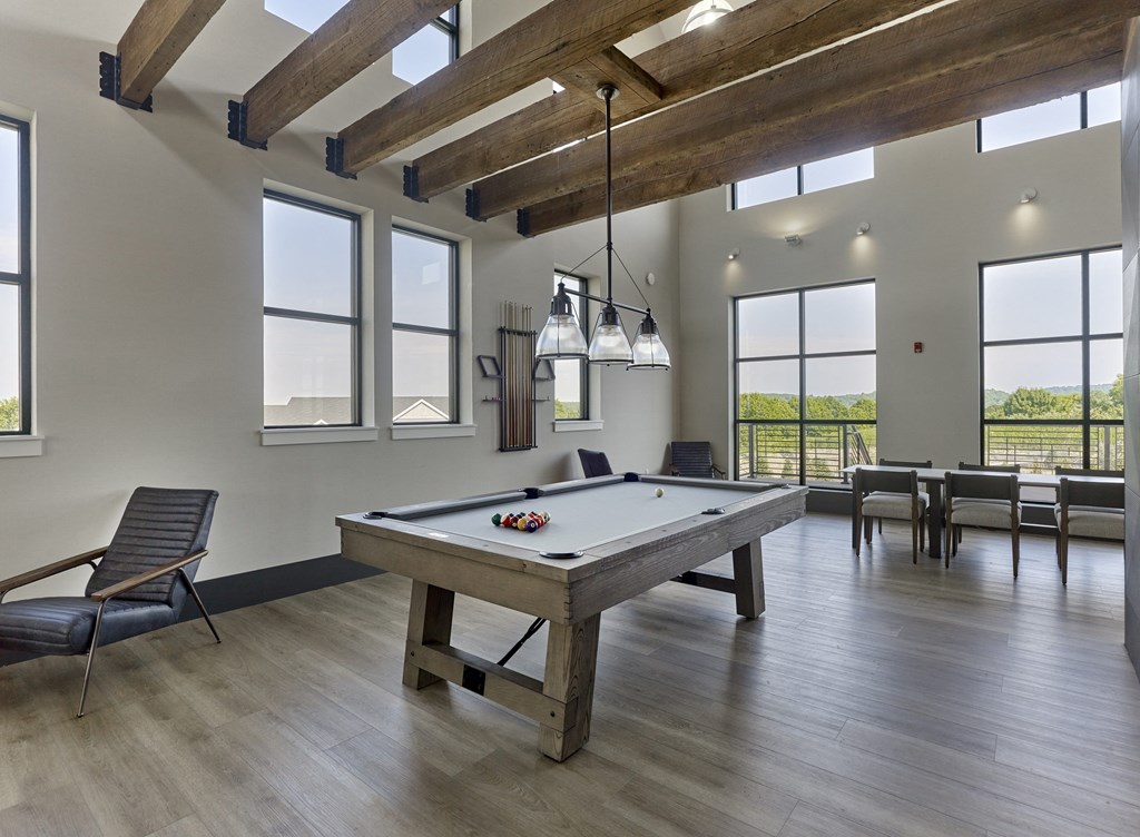 an open living room with a pool table and chairs