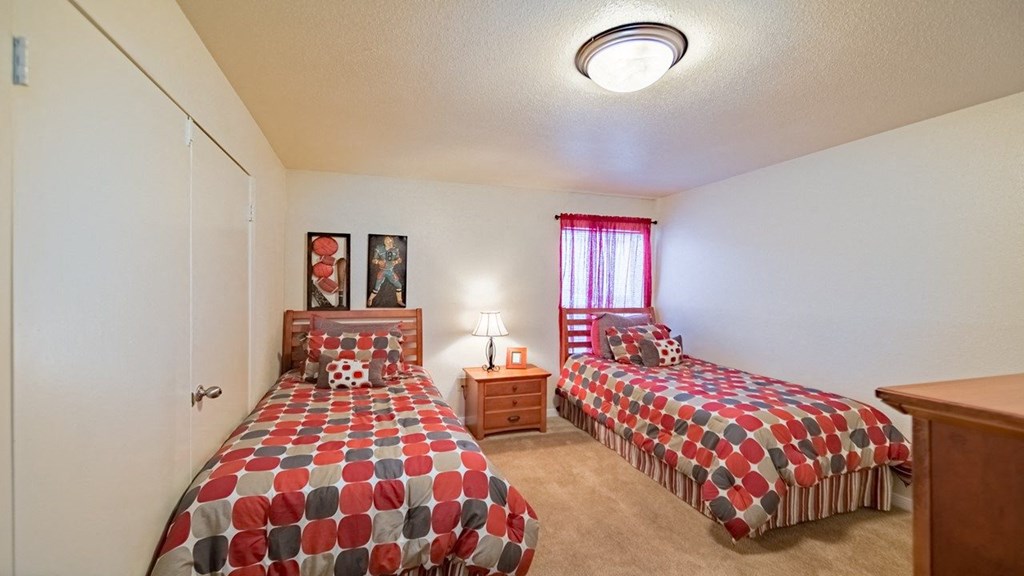 a bedroom with two beds and a dresser and a window