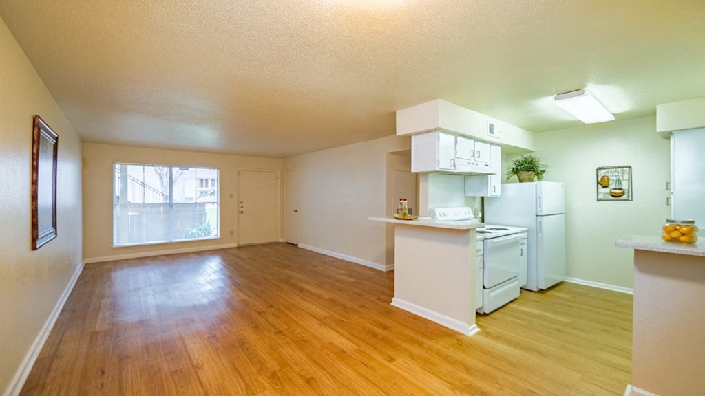 an empty living room and kitchen with a wood floor
