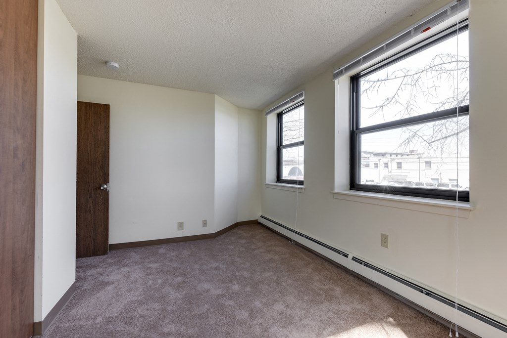 an empty living room with two windows and a door