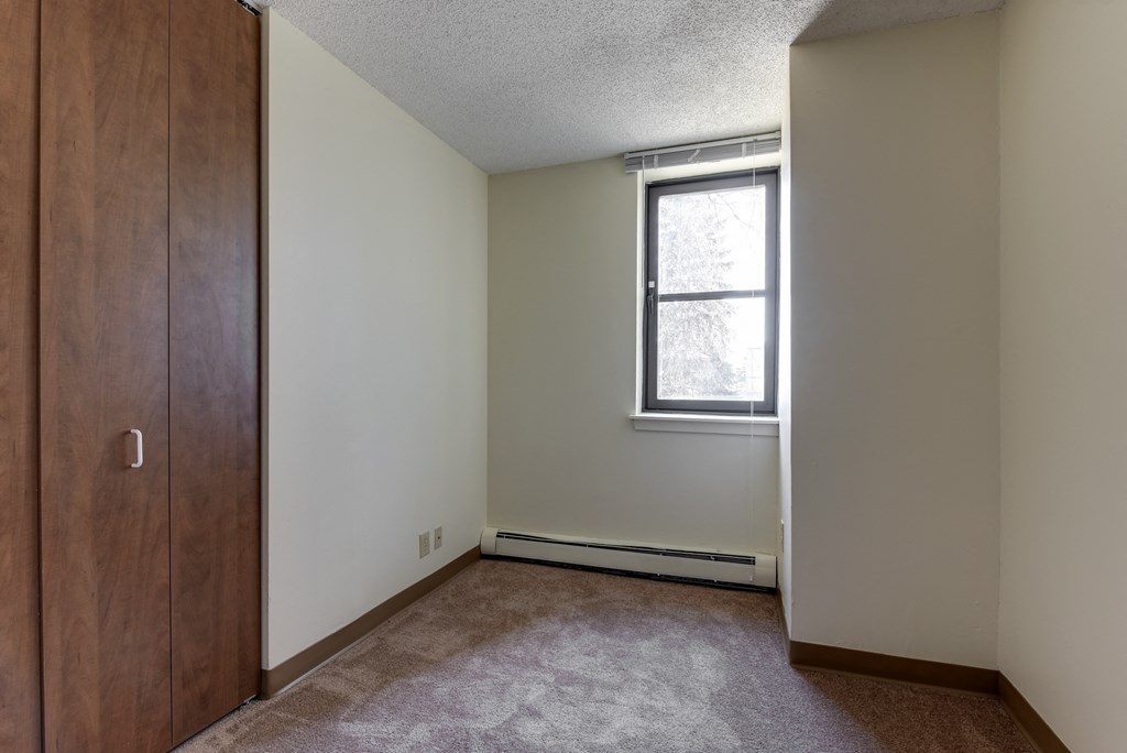 an empty bedroom with a window and a closet