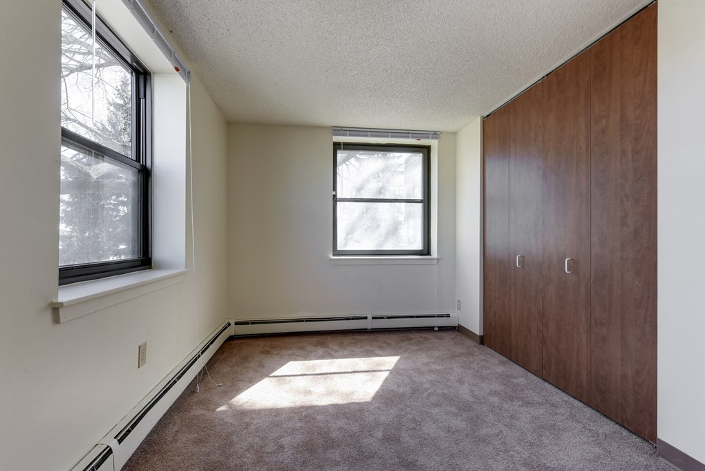 an empty living room with two windows and a closet