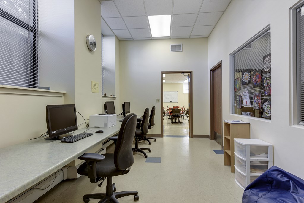a room with a long desk with a computer and chairs