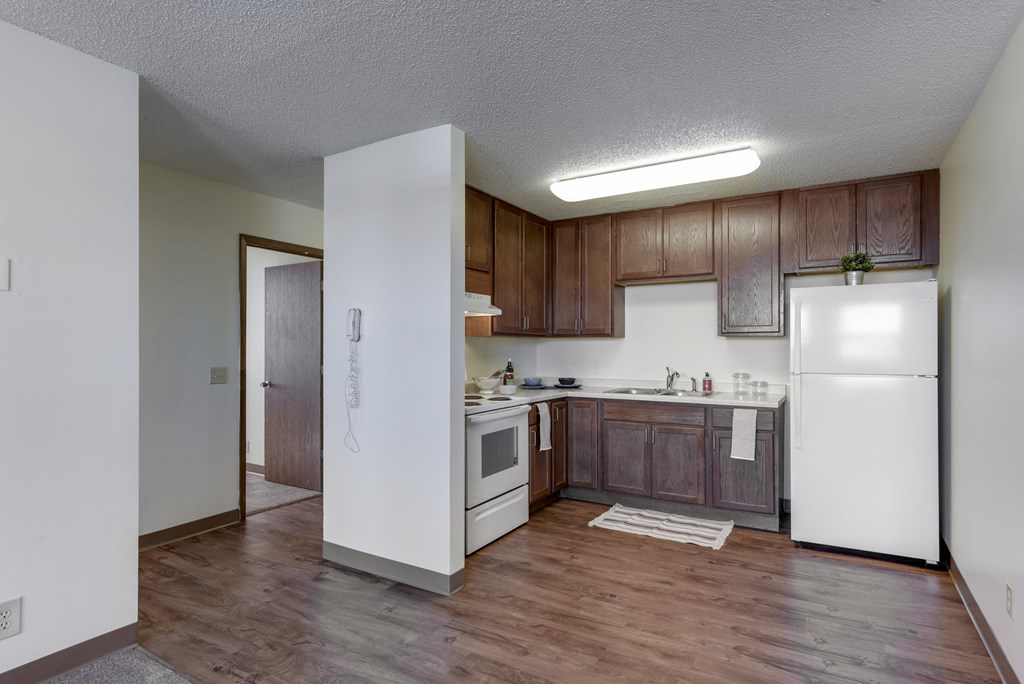 an empty kitchen with white appliances and wooden cabinets