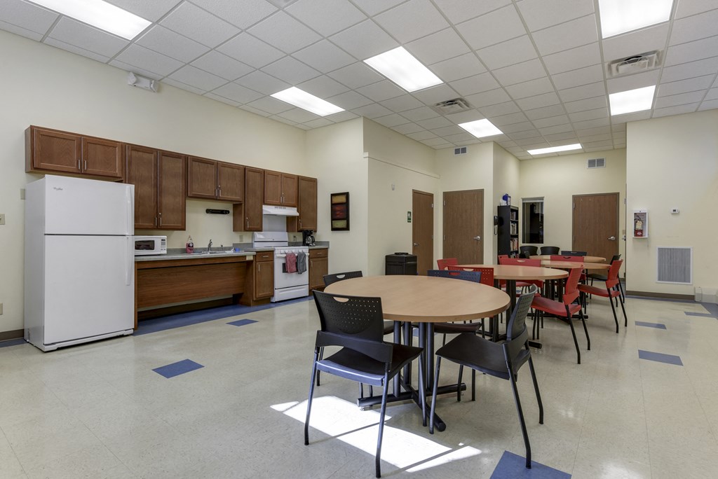 a multipurpose room with a table and chairs and a kitchen