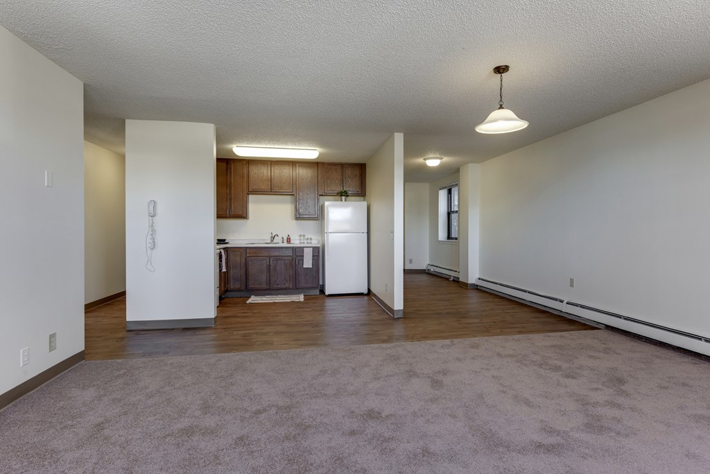 an empty living room and kitchen with white walls and wood flooring