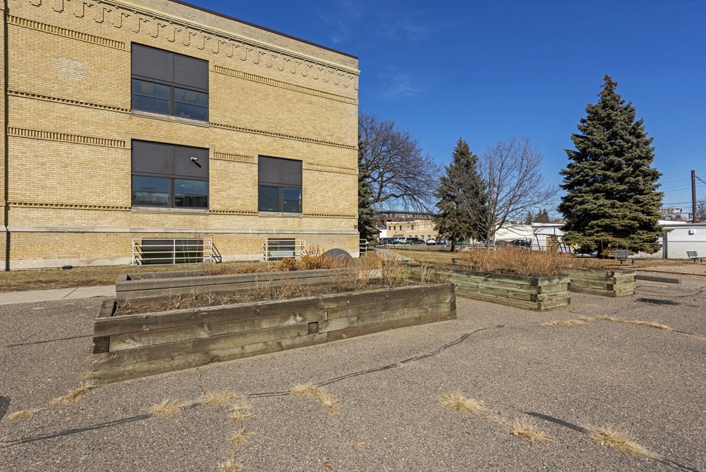 a brick building with benches and trees in front of it