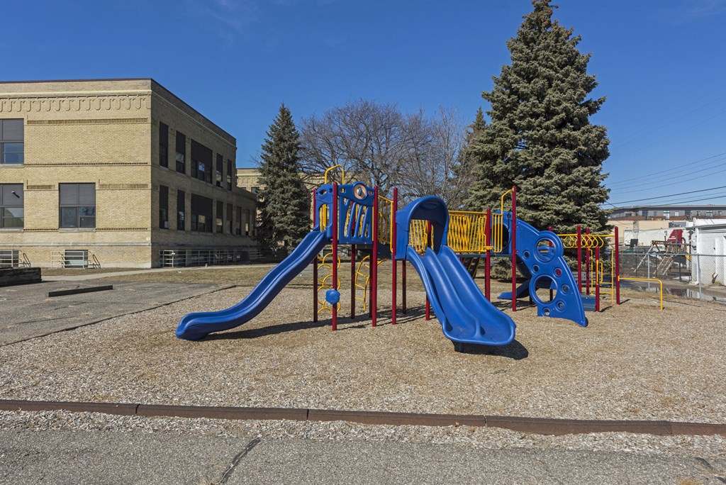 a playground in front of a building with a blue slide