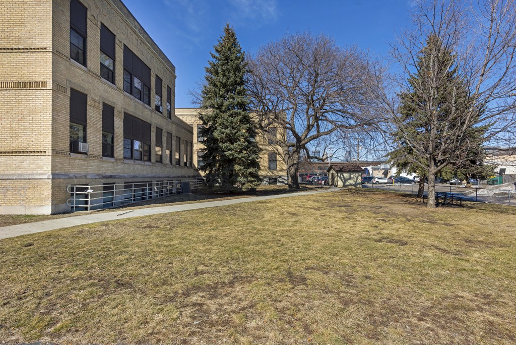 a large brick building with a lawn and trees