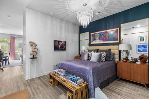 A bedroom with a purple bed and a wooden nightstand at The Quarter Lofts Apartments, Jackson, MS, 39216