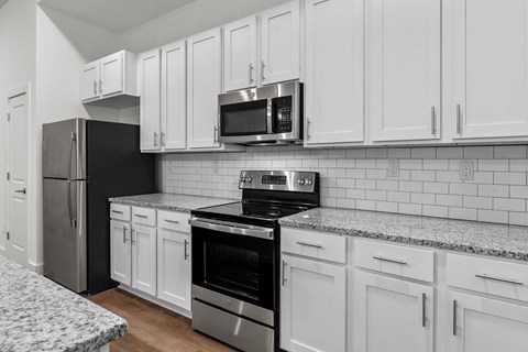 A kitchen with white cabinets and black appliances.