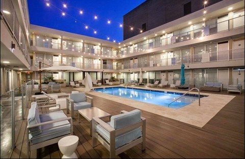 A large outdoor pool area with lounge chairs and a hot tub at night.