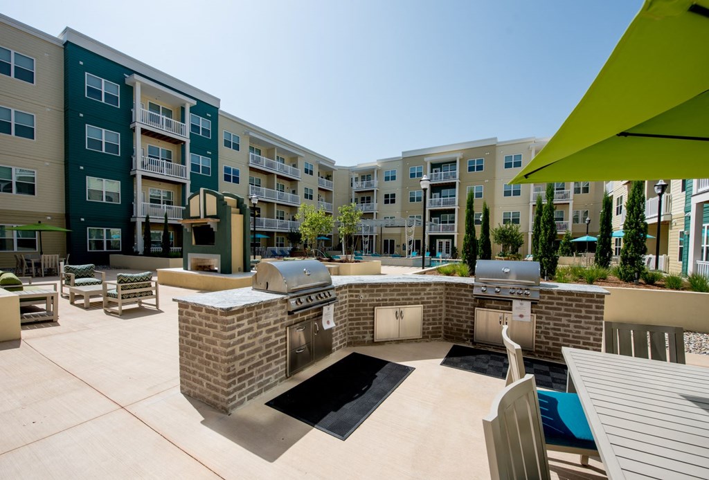 an outdoor patio with two grilling stations and an apartment building
