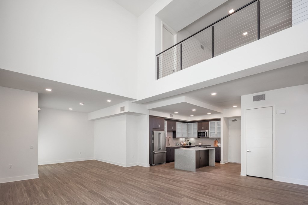 a living room and kitchen with white walls and wood floors