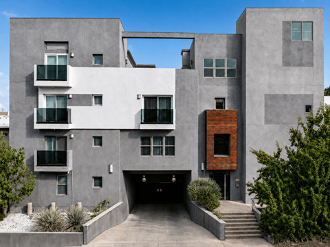 A modern house with a grey exterior and a red brick door.