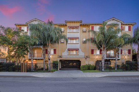 a street view of an apartment building with palm trees