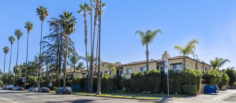 A row of palm trees in front of a house.