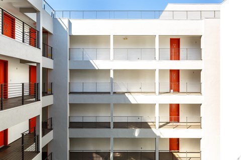 a white apartment building with red doors and balconies