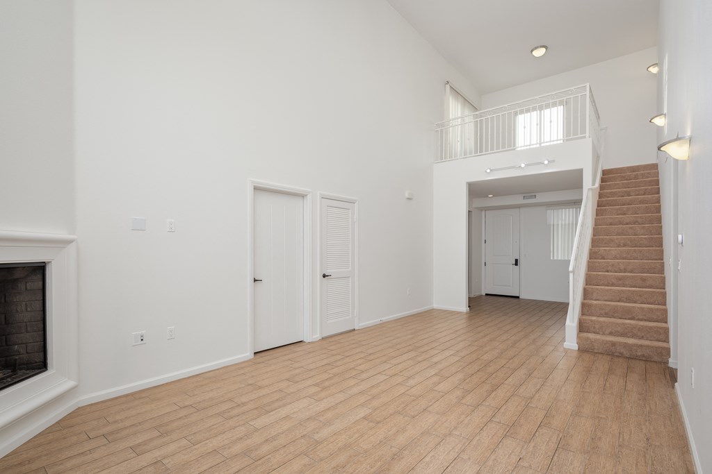 a living room with a staircase and a fireplace and a hard wood floor