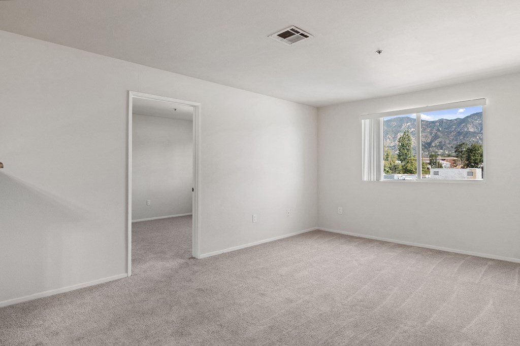 an empty room with white walls and a window with a mountain view