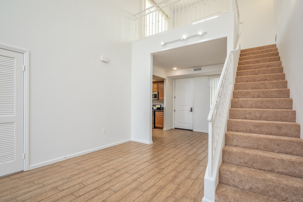 a living room with stairs and a door to a kitchen