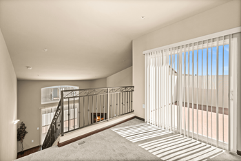 a living room with a staircase and a large window with white blinds