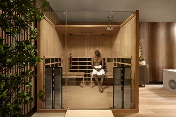 A man is sitting in a sauna with wooden walls and a bench.