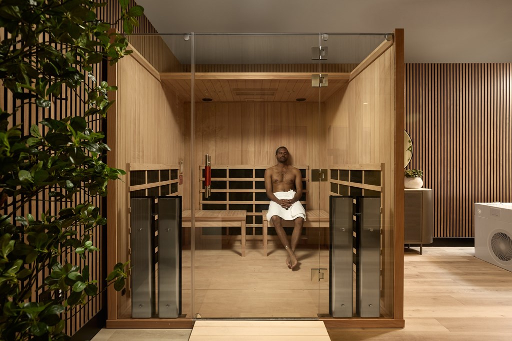 A man is sitting in a sauna with wooden walls and a bench.