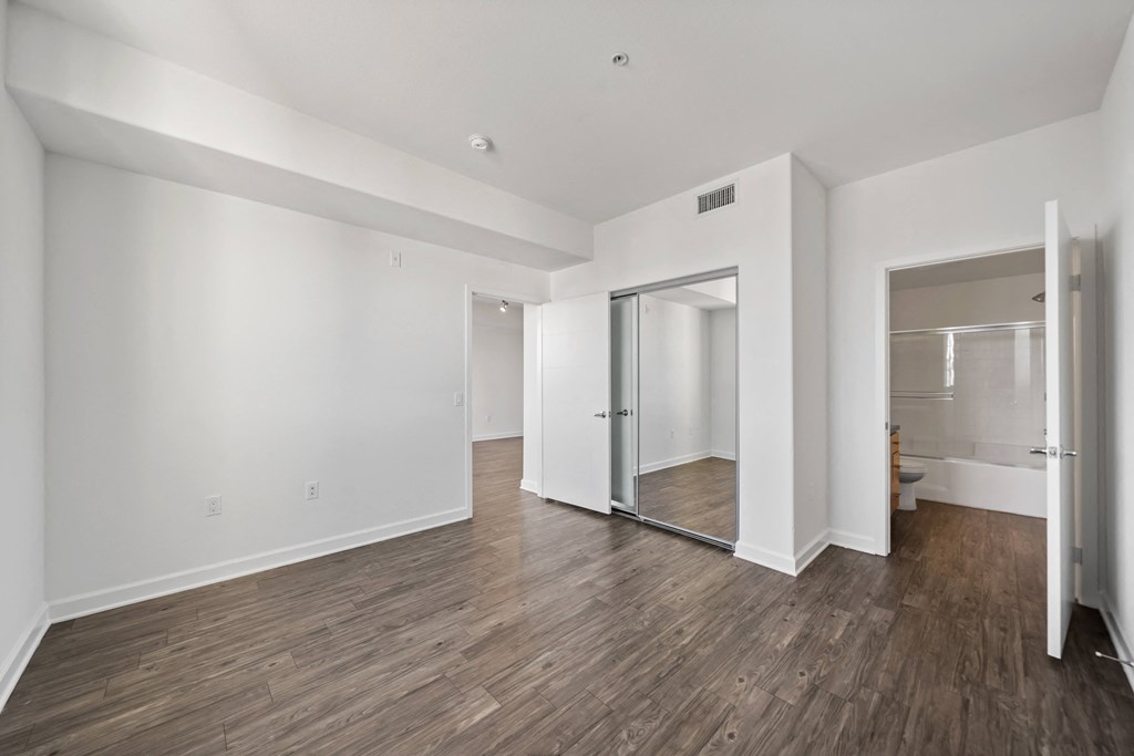 a living room with white walls and a sliding glass door to a bathroom
