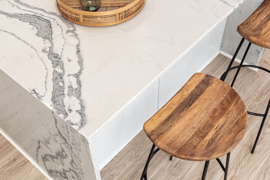a kitchen with marble counter top and wooden chairs