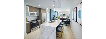 A modern kitchen with a marble island and bar stools.