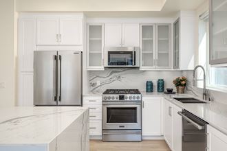 a white kitchen with stainless steel appliances and white cabinets