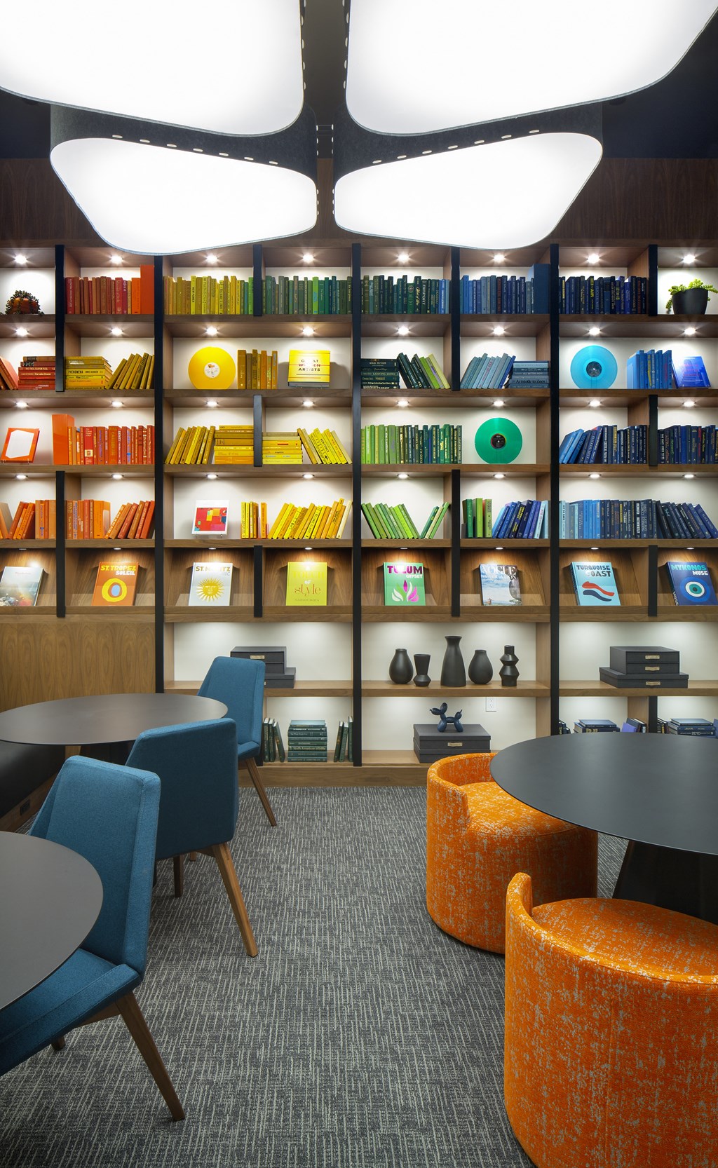 a room with tables and chairs and a wall of bookshelves