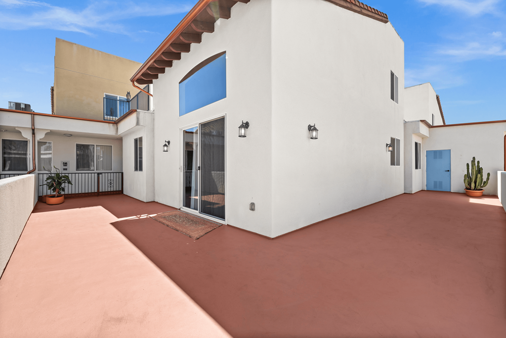 a white house with a patio and a blue door at Le Blanc Apartment Homes, Canoga Park