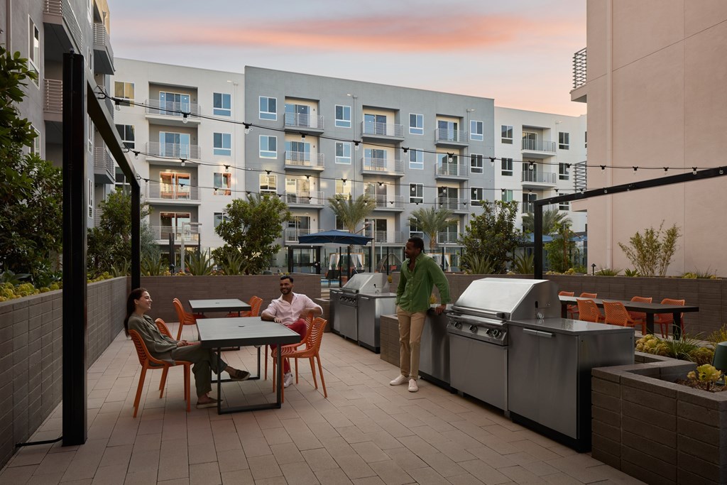 Two people are standing on a patio with a table and chairs.