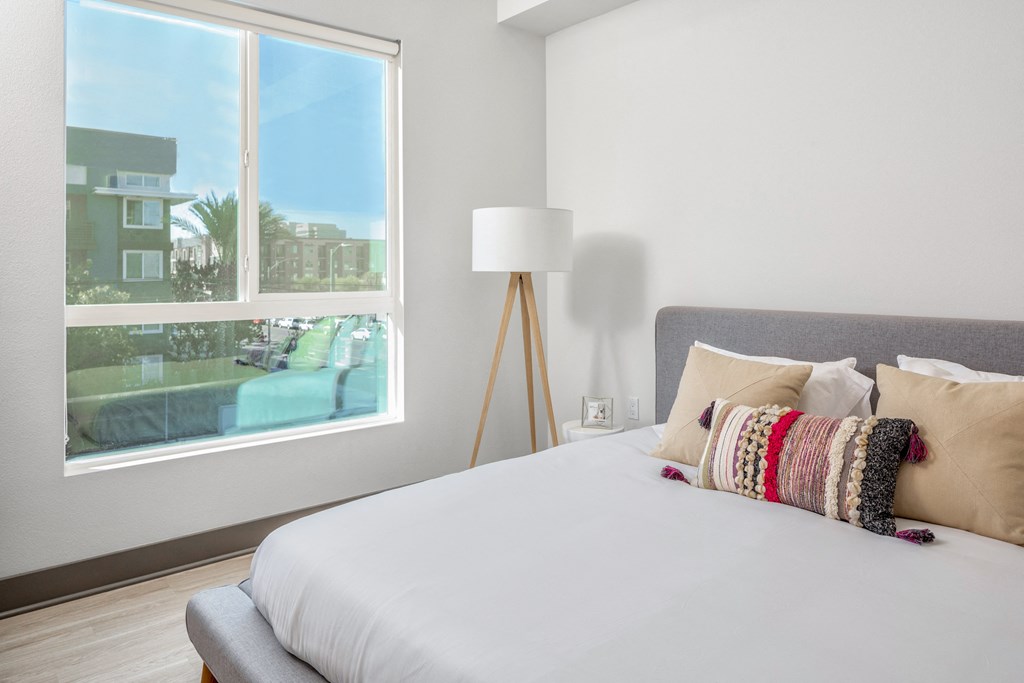 a bedroom with a large window and a bed with pillows