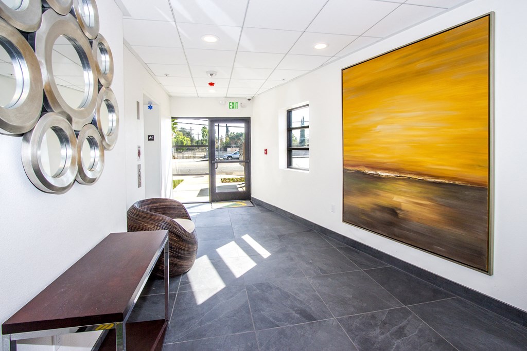 a hallway with paintings on the wall and a table and chairs