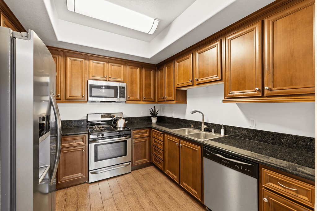 a kitchen with wooden cabinets and stainless steel appliances at Le Blanc Apartments, Canoga Park, CA, 91304