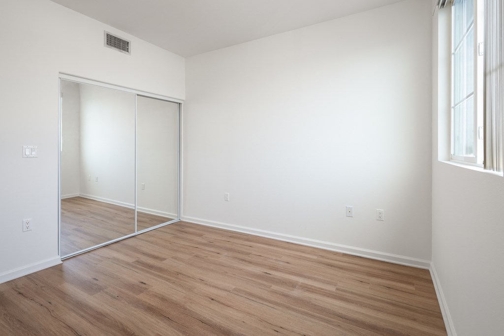 an empty room with white walls and wood flooring