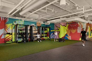 A man is walking in a room with a colorful mural on the wall.