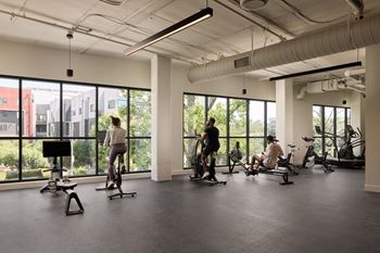 A gym with people exercising and a view of the city.