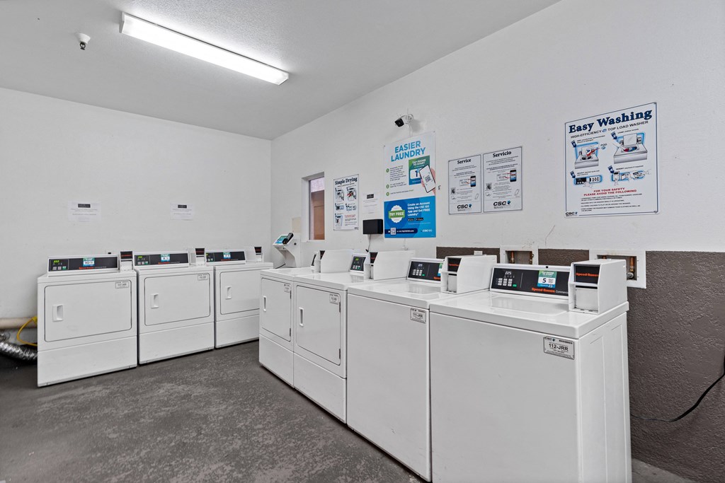 a row of washers and dryers in a laundromat with white machines