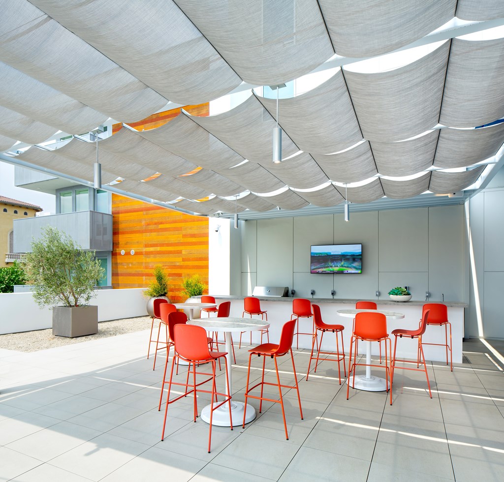 a dining area with red chairs and tables under a white canopy