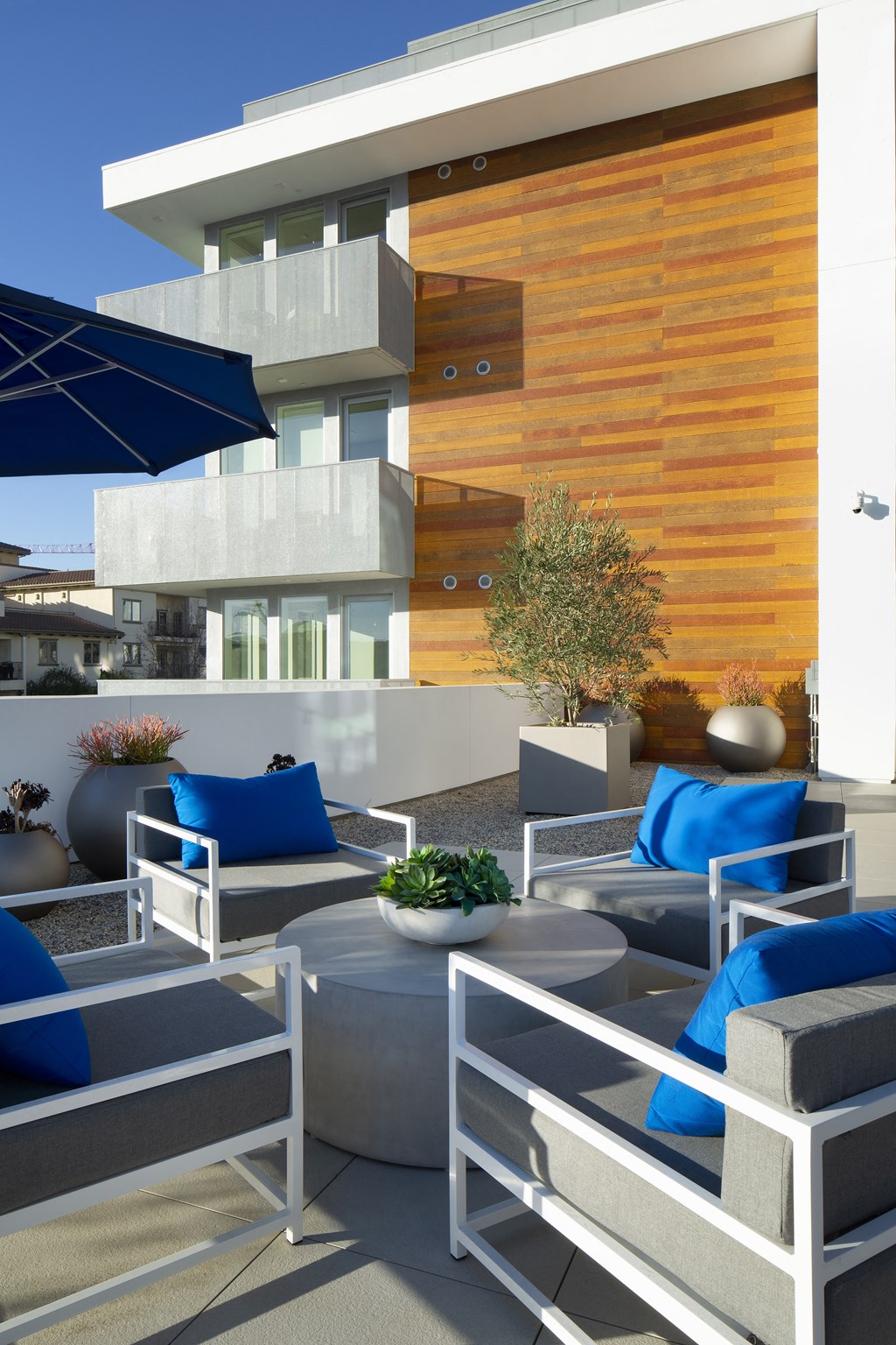 a patio with blue chairs and tables and a building in the background