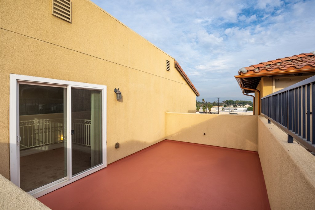 a balcony with a door and a yellow wall and a patio