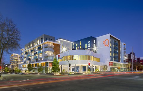 A modern building with a large white circular entrance is illuminated at night.