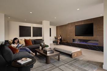A woman is sitting on a couch reading a book in a modern living room.