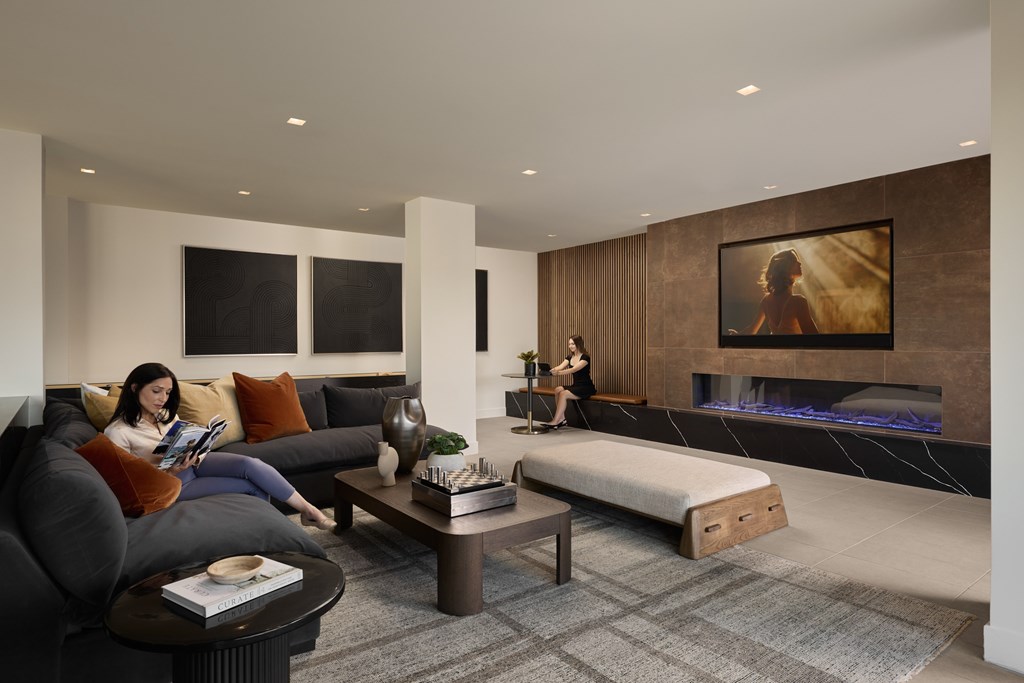 A woman is sitting on a couch reading a book in a modern living room.