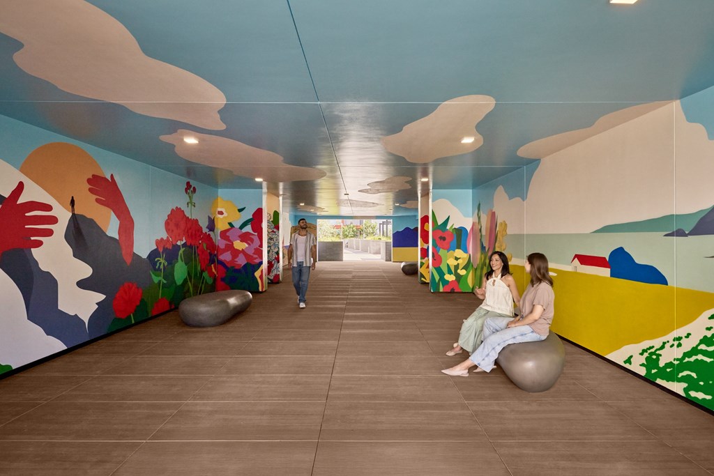 Two women sitting on exercise balls in a room with colorful murals.