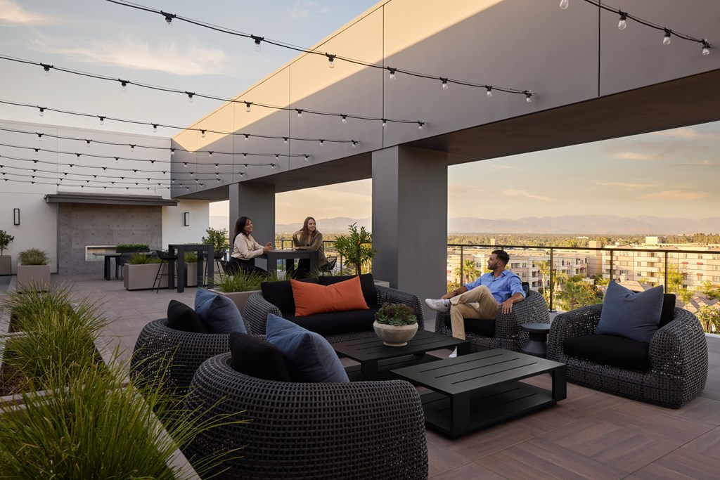 A group of people are sitting on a patio with a view of the city.